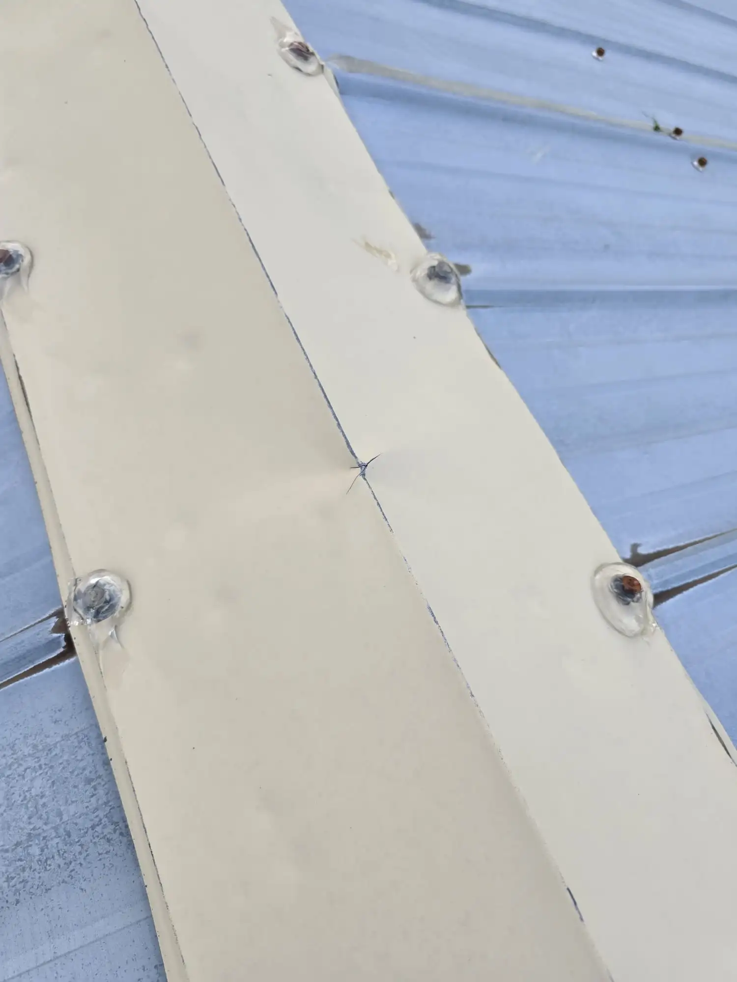 Mechanical damage piercing metal ridge caps, documented during a roof inspection in Calgary